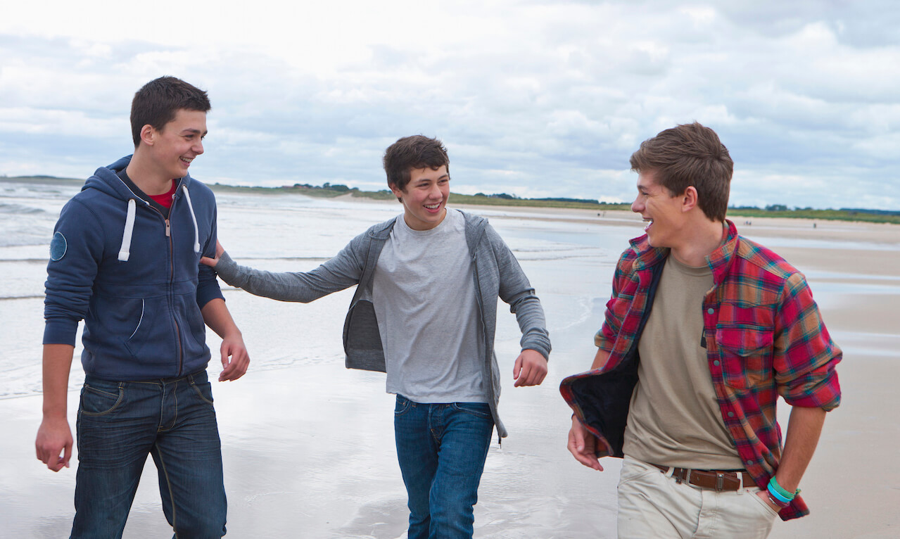 Teenage boys walking on beach, Northumberland, UK