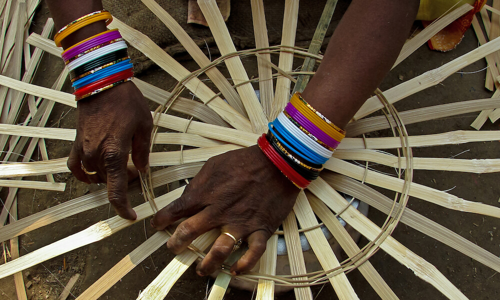 Close view of hands of woman weaving basket