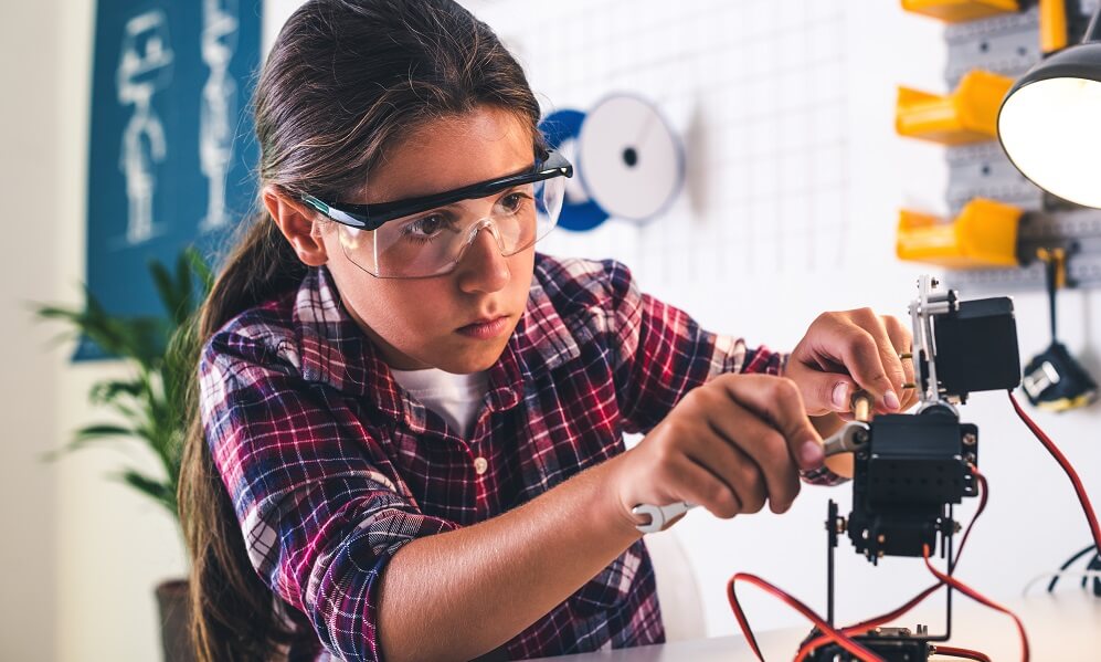 Girl in a robotics laboratory adjusts robot arm model