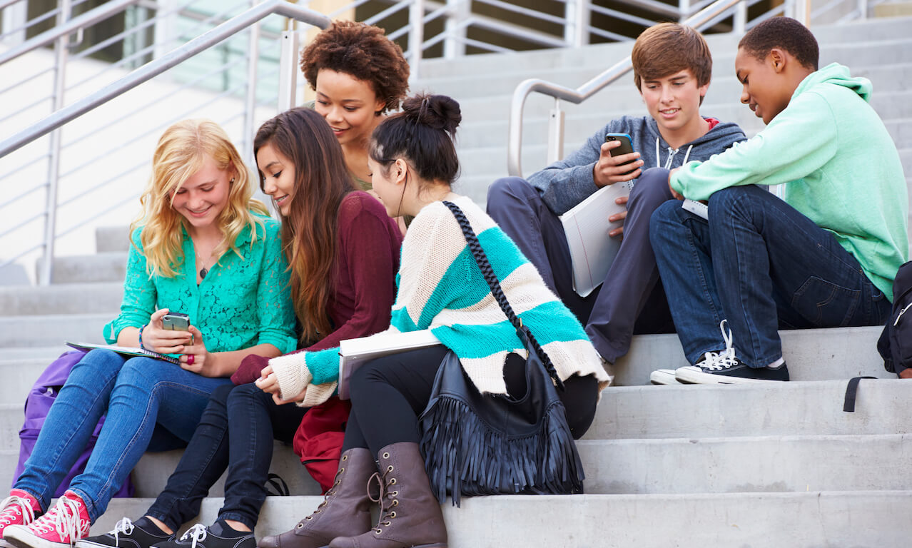 High school students sitting on stairs with phones