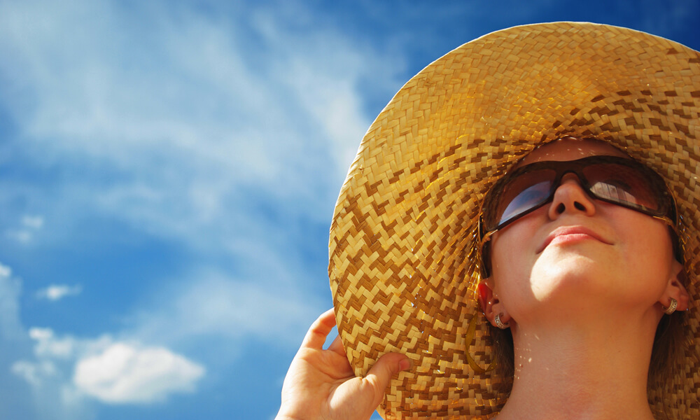 Portrait of young woman in straw hat and sunglasses