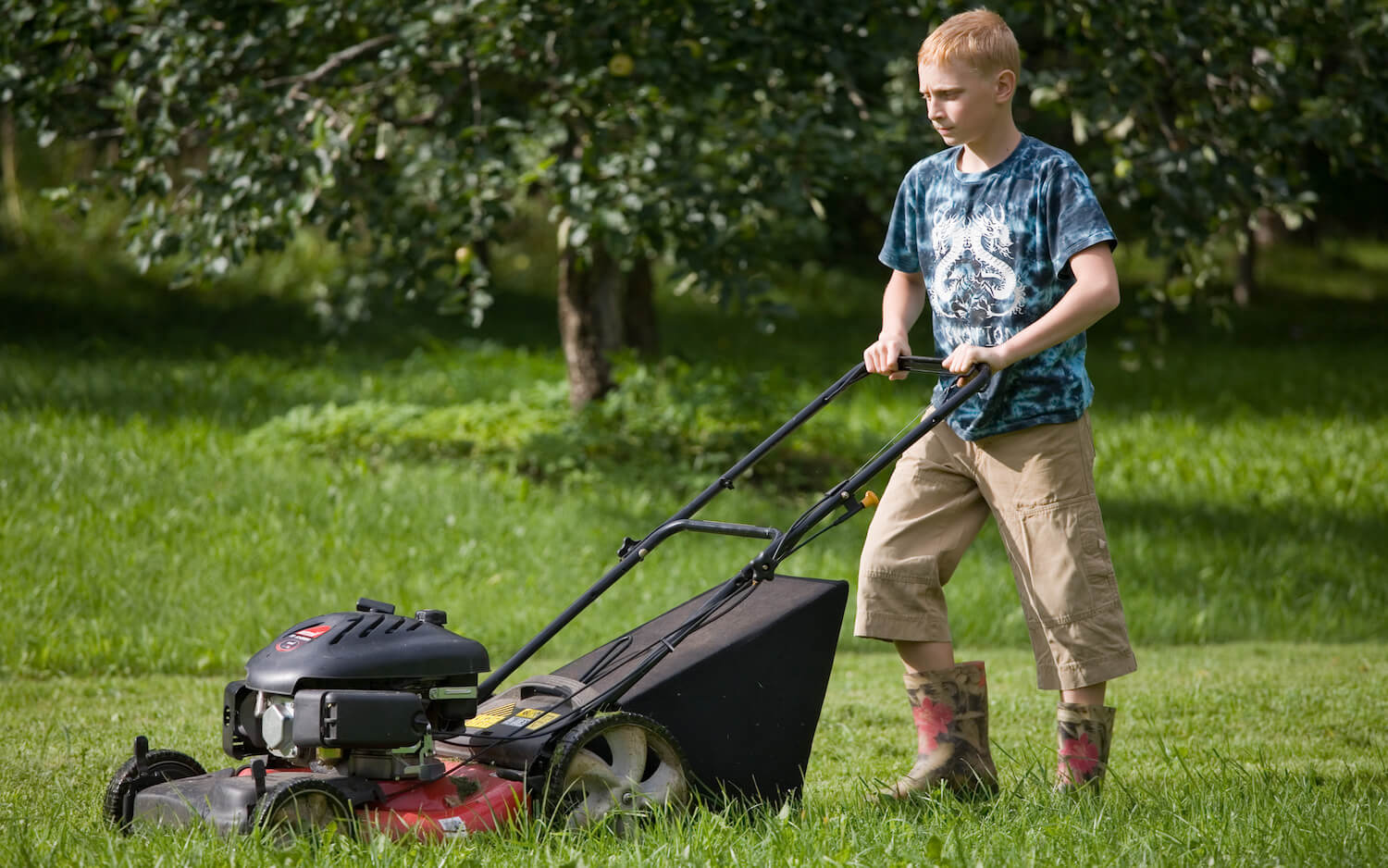 Teenage Boy Mowing Lawn Using Lawn Mower