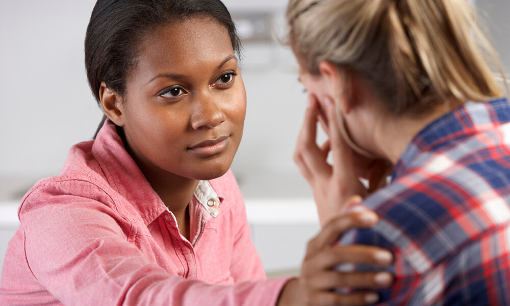 Medical professional consoles a teenage girl who is upset