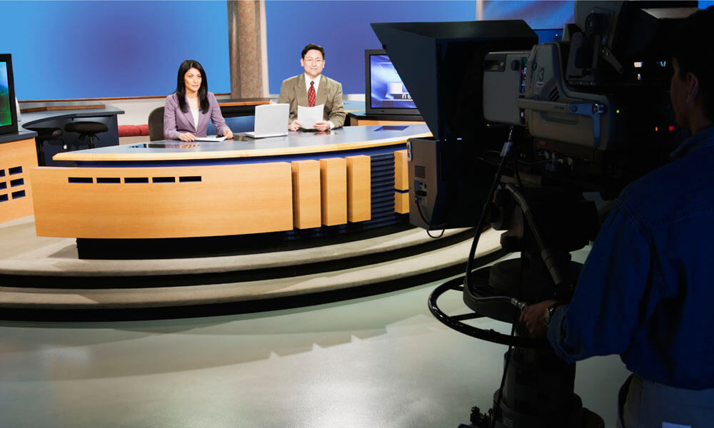 Anchor people on set in TV newsroom