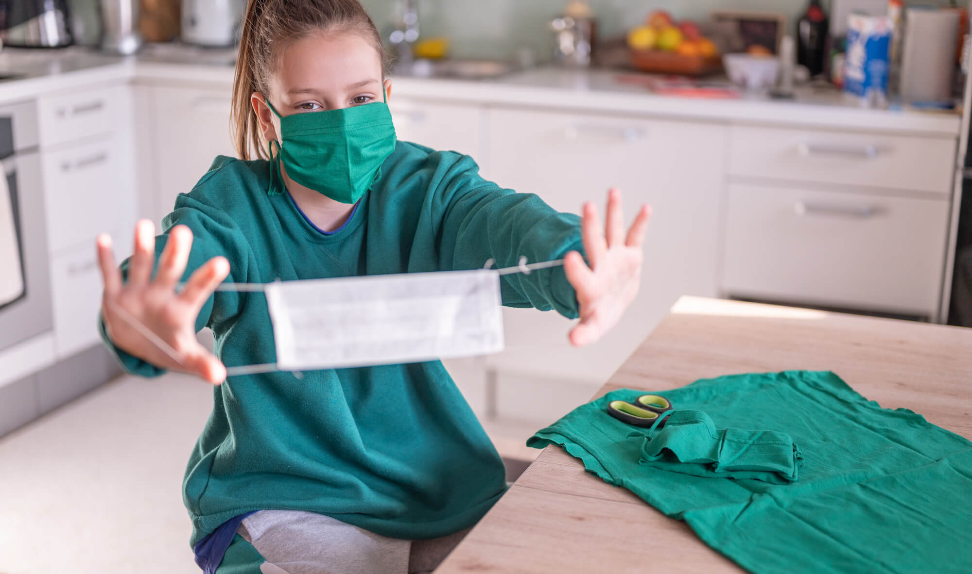 Young girl making a protective face mask at home during the coronavirus Covid-19.