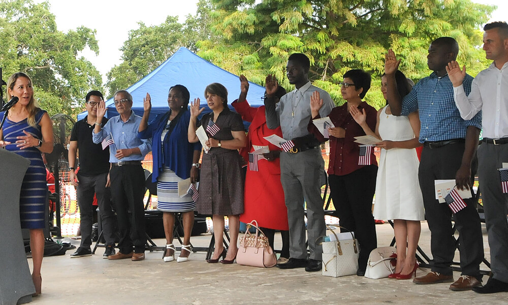Candidates for U.S. citizenship holding up their right hands while being administered the Oath of Allegiance