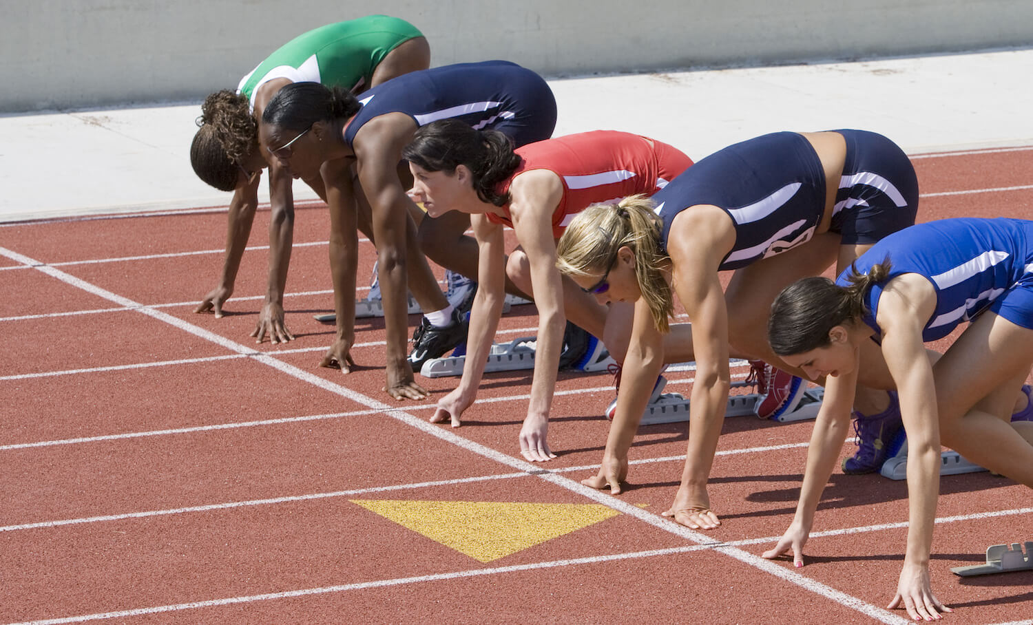 Multiethnic female athletes at starting line on race track