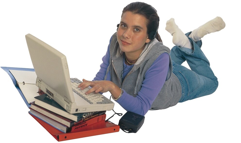 Student lying down with laptop computer and books