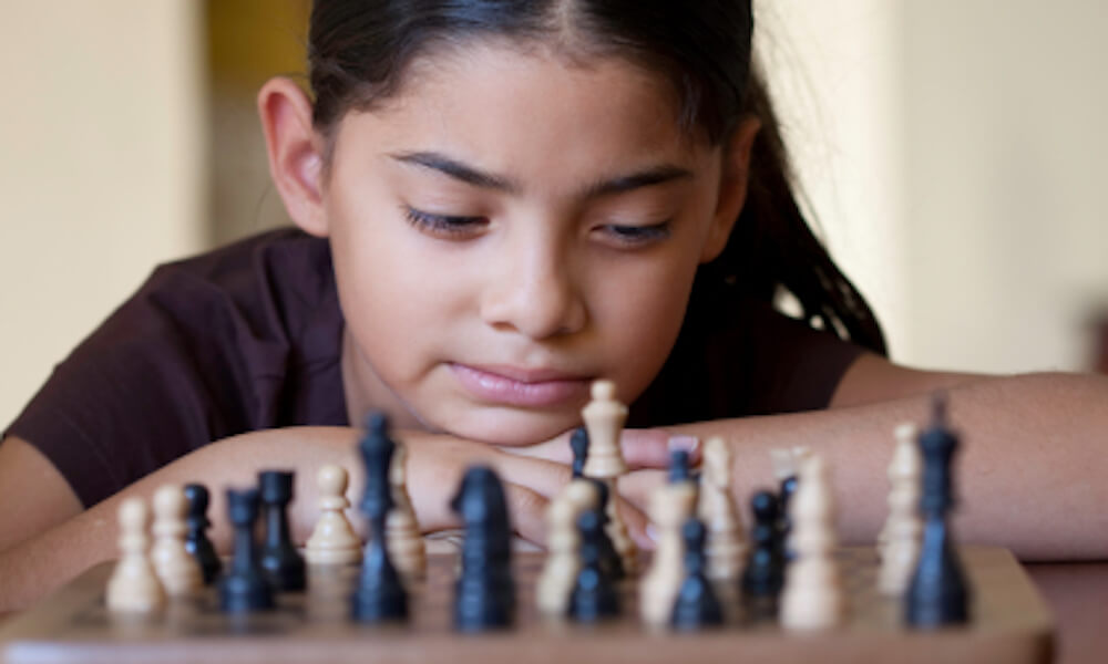 Young girl thinking about the next chess move