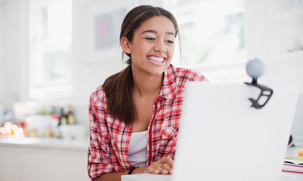 Smiling teenage girl enjoying video chat on laptop