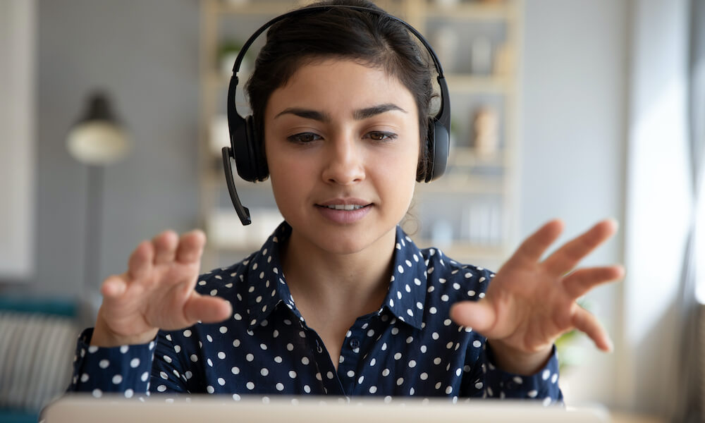 Young woman wearing a headset using a laptop for a video conference