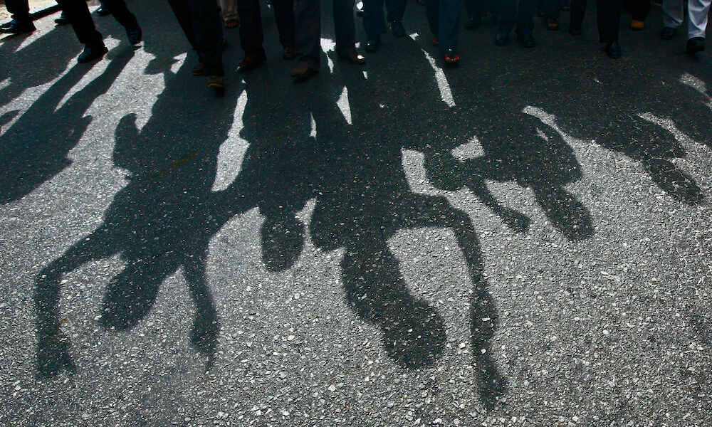 Protesters cast a shadow as they march on a street