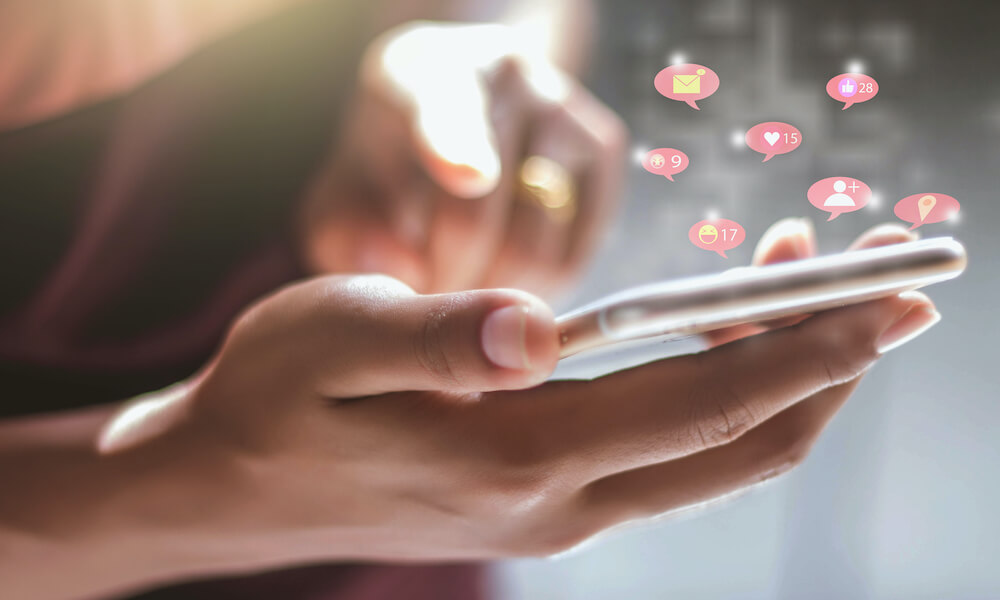 Close-up of someone using a smartphone, with social media notifications shown above the screen Close-up of someone using a smartphone, with social media notifications shown above the screen