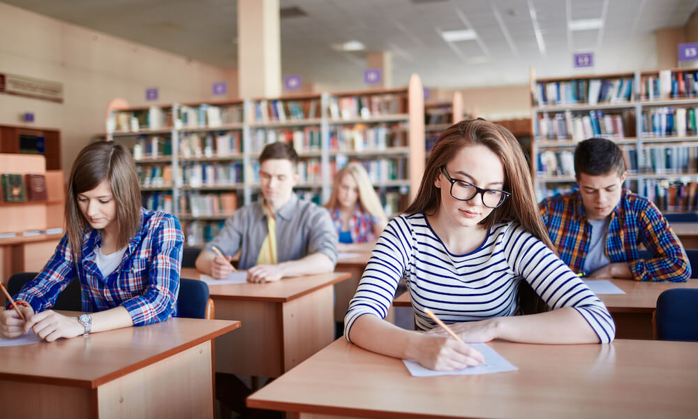 High school students taking an exam in a school library