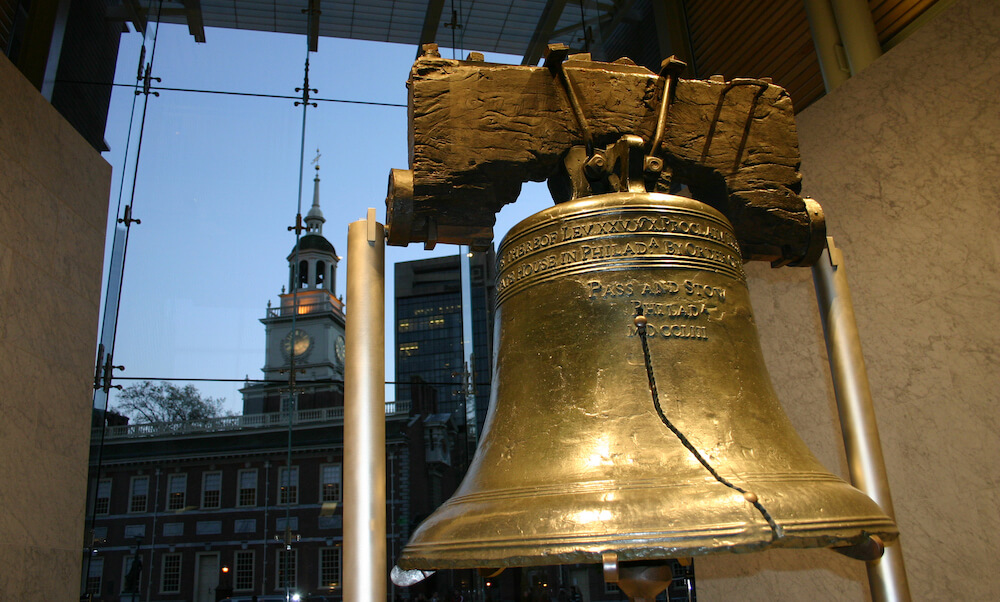 Close-up shot of the Liberty Bell with Independence Hall in the background at dusk. Located in downtown Philadelphia, this monument to liberty continues to draw crowds on a daily basis.