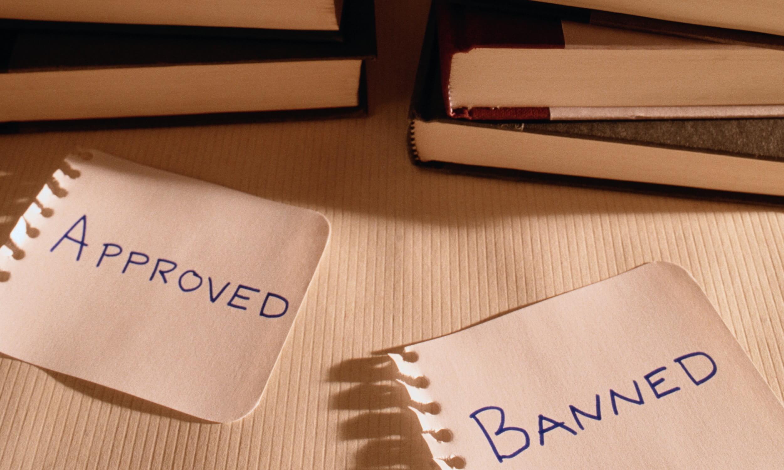Two stacks of books; one labeled Approved and the other labeled Banned