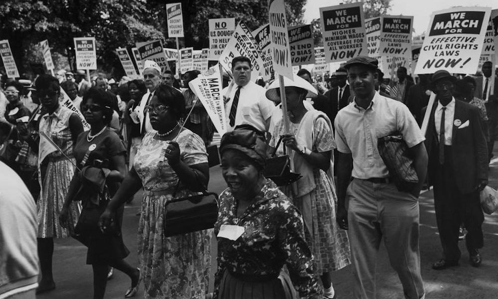 Civil Rights demonstrators march in the streets, carrying signs