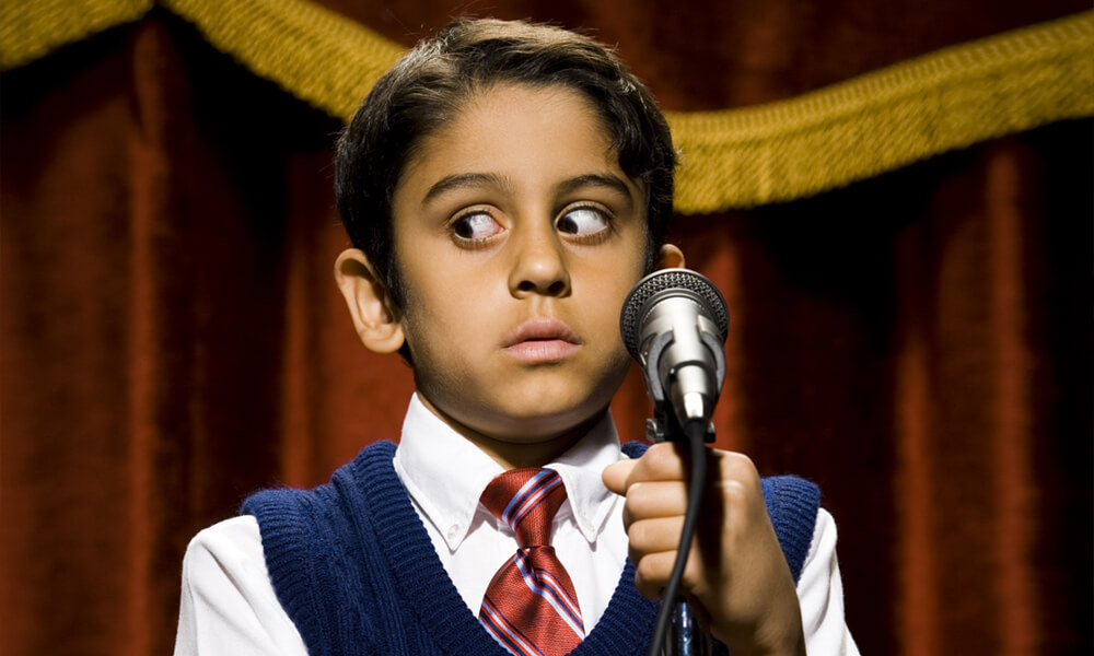 Boy standing on stage with microphone and big eyes