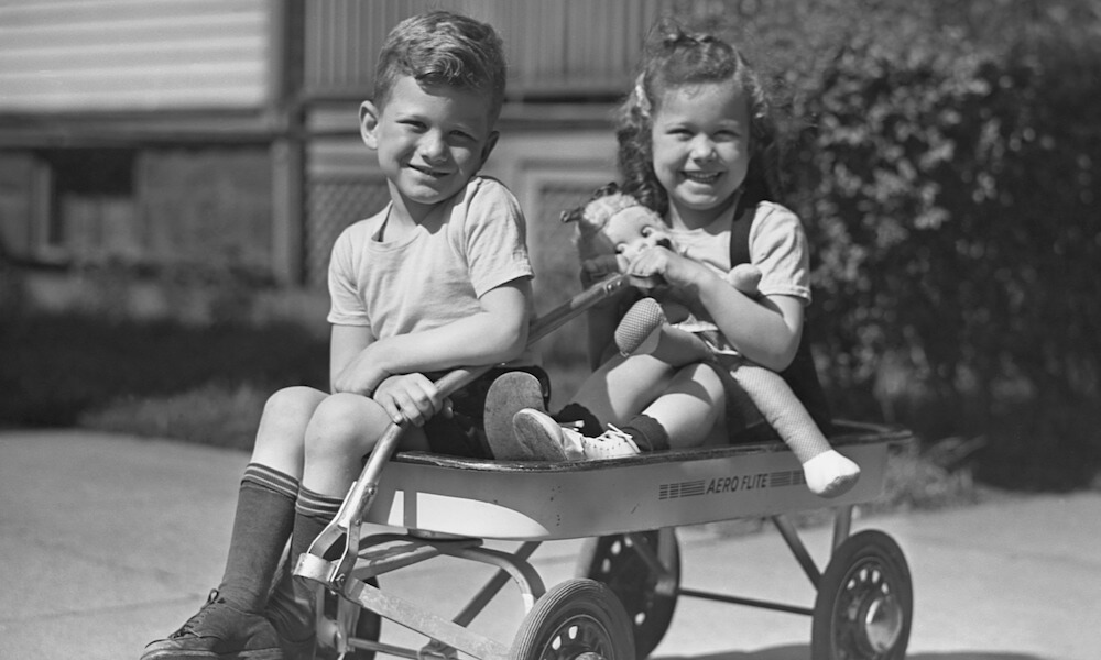 Children with a doll sitting in a wagon.