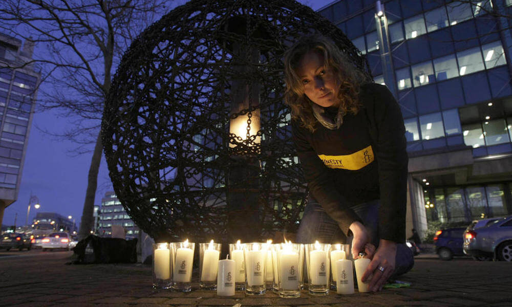 An Amnesty International volunteer takes part in a candlelit vigil to celebrate 60 years of human rights