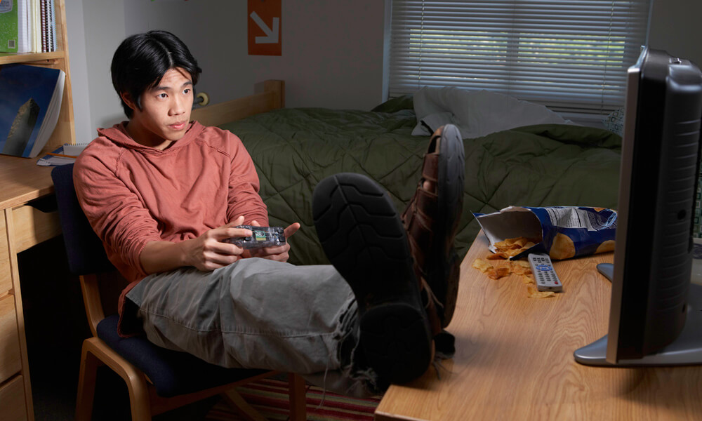 Young man playing video game in dorm room