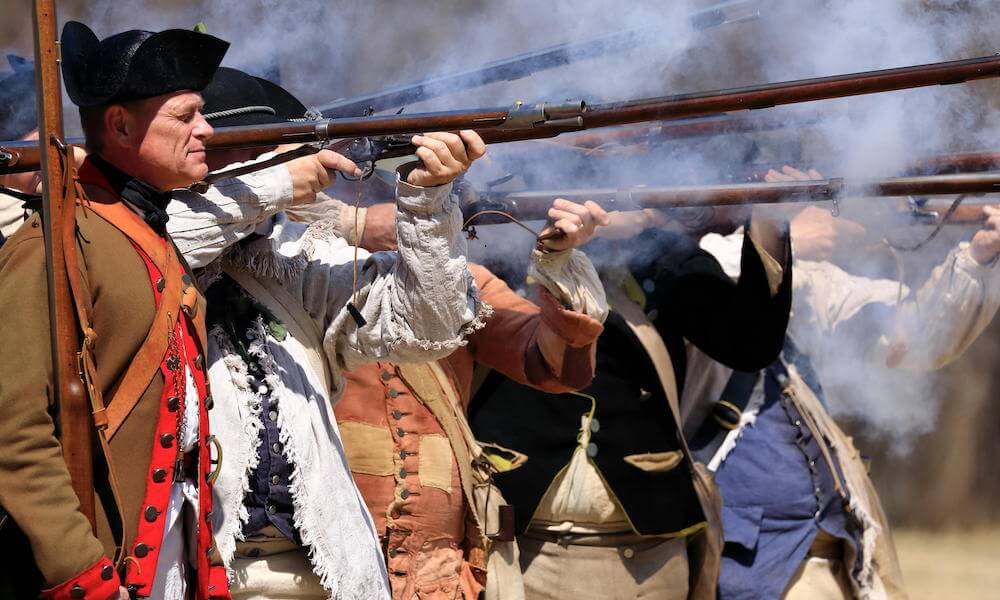 Reenactors of American Continental Army firing muskets in Jockey Hollow Historical Park during annual Jockey Hollow Encampment, Harding, New Jersey USA