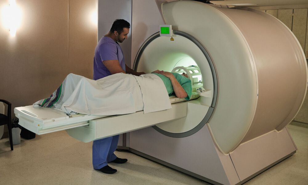 Male radiologist doing CT-Scan on female patient in examination room