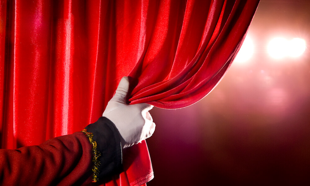 Audience silhouette and curtain: Audience facing the stage during an intermission with the curtains drawn