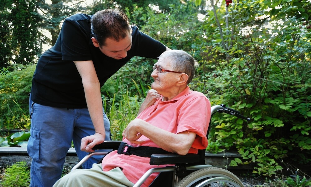 Man taking care of an old lady in a wheelchair