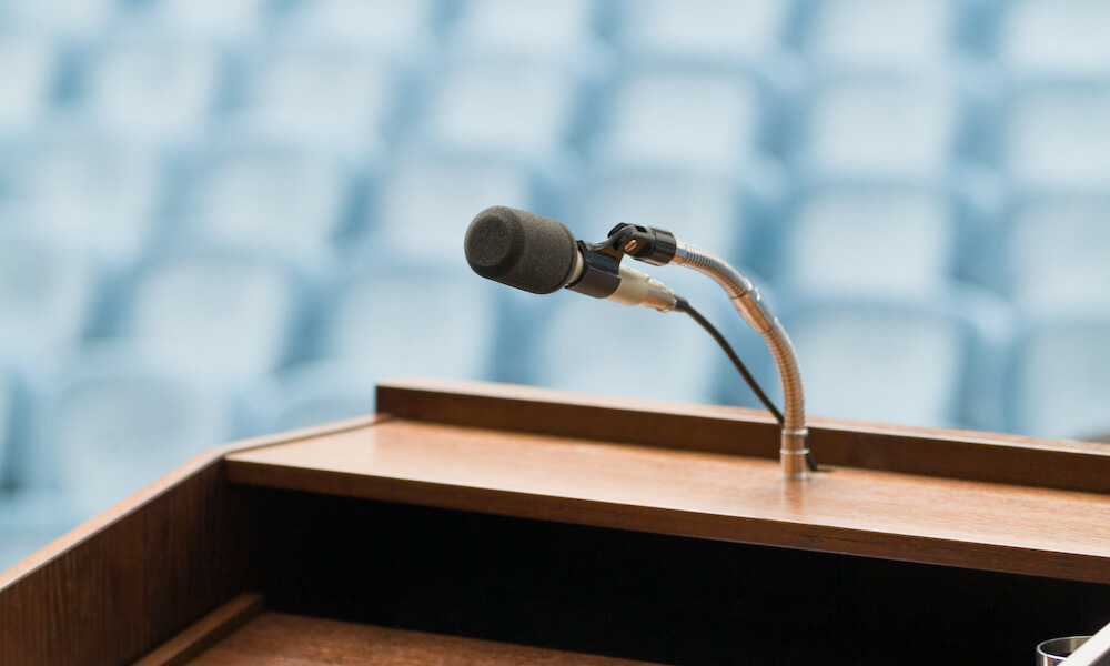 Podium with speaker's paper, and microphone in empty auditorium