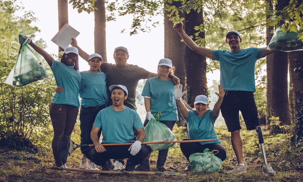 Multi-ethnic group of people, cleaning together in public park, saving the environment, disability man helping them.