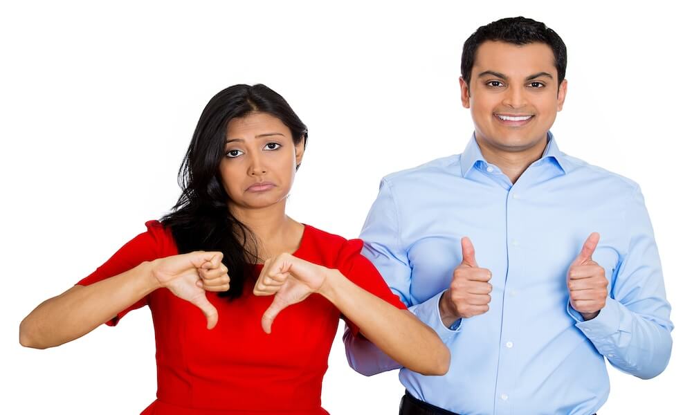 Closeup portrait of conflict couple, man woman. One excited happy smiling optimistic, showing thumbs up, other serious concerned unhappy thumbs down, isolated on white background. Emotion contrasts; Shutterstock ID 176698955; Requestor Name/Material Code: -