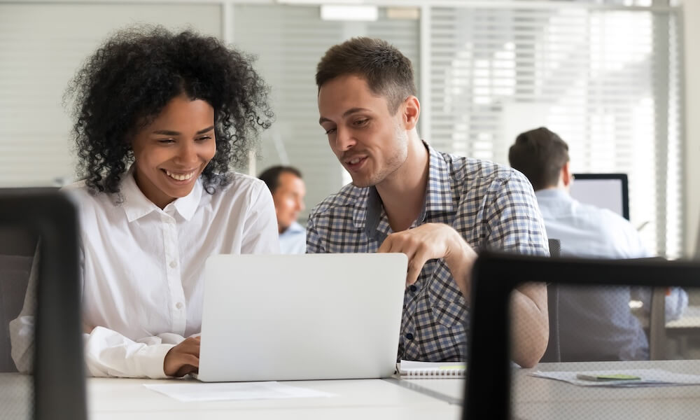 Friendly male mentor colleague teaching coaching female intern explaining online project Friendly male mentor colleague teaching coaching female intern explaining online project