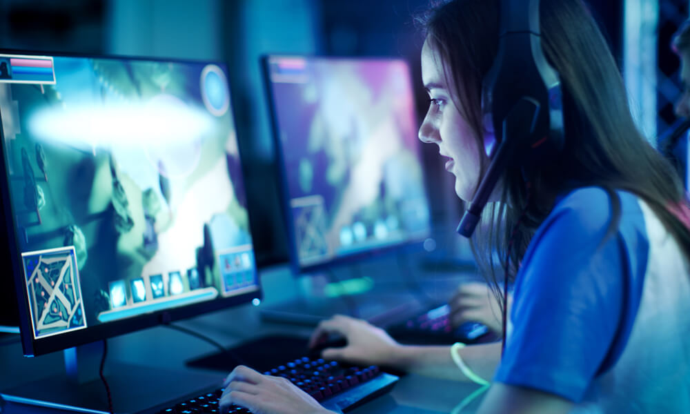 Professional Girl Gamer Plays in MMORPG/ Strategy Video Game on Her Computer. She's Participating in Online Cyber Games Tournament, Plays at Home, or in Internet Cafe. She Wears Gaming Headset