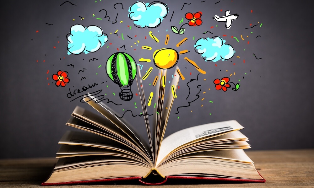 Open book laying on table with art of clouds, air plane, flowers, sun, and hot air balloon