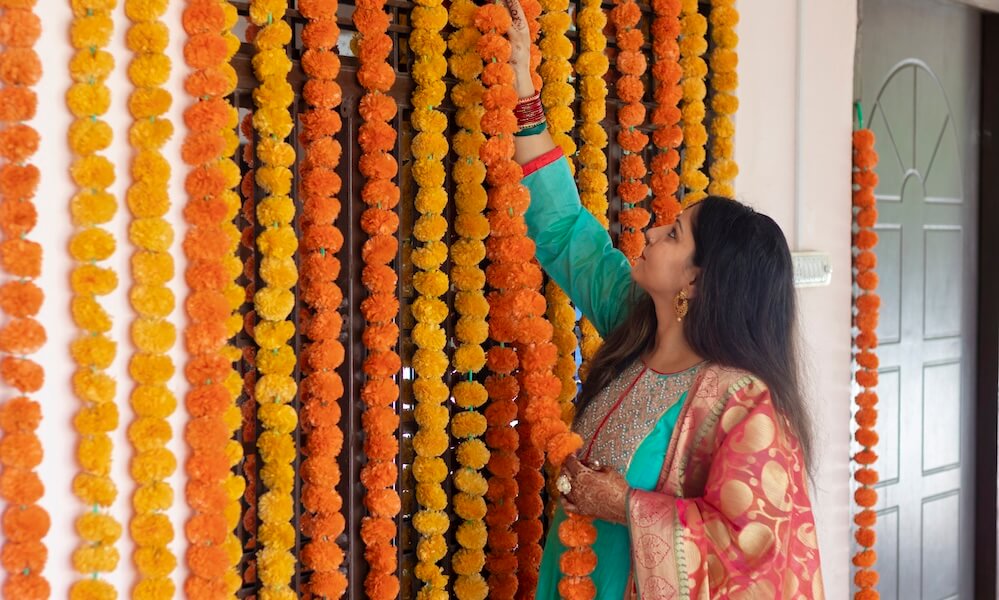 Indian woman in a traditional outfit decorating house with flowers for Diwali