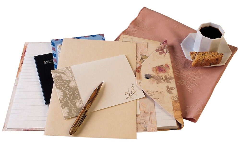 Stationary, papers, and a pen arranged next to a cup of coffee.