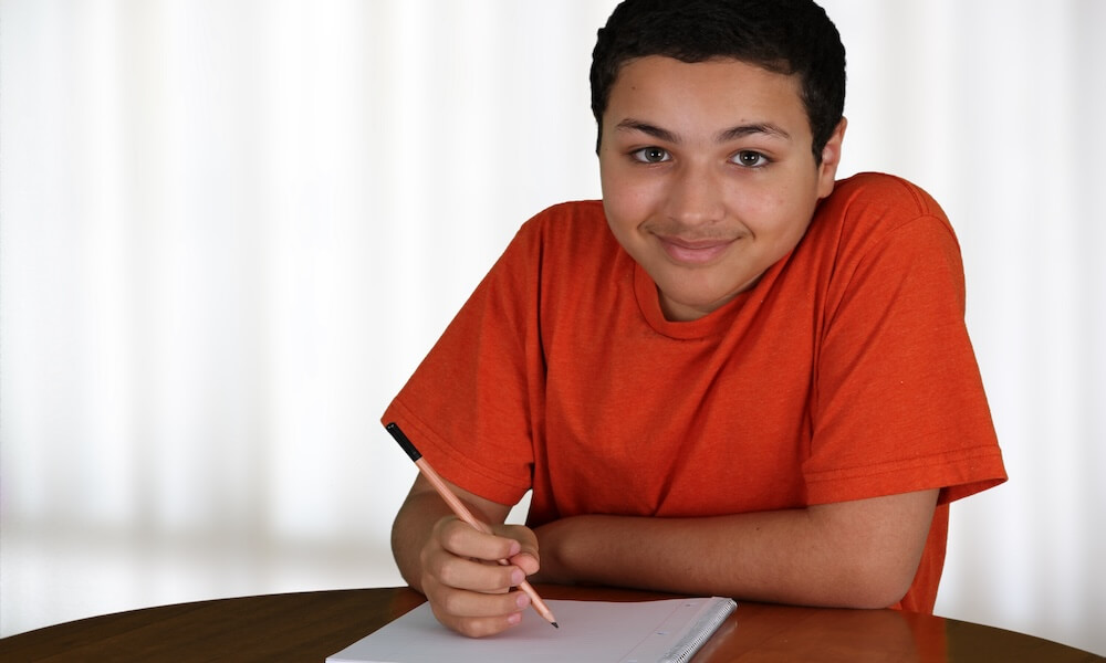 Teen boy doing homework after school at the table
