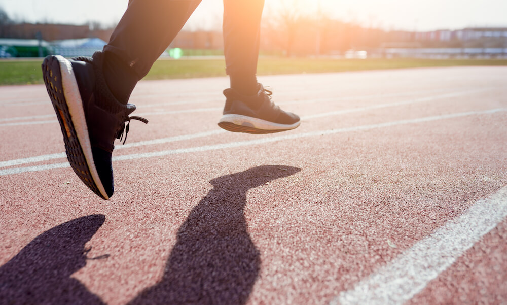 Photo from side close-up of athlete's feet running around stadium