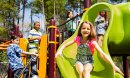 Five elementary-age children play during school recess or at a park setting. Playground equipment, slide.