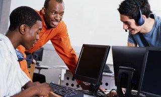 Three men using computers in an office setting
