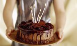 Woman's hands holding a chocolate cake with candles