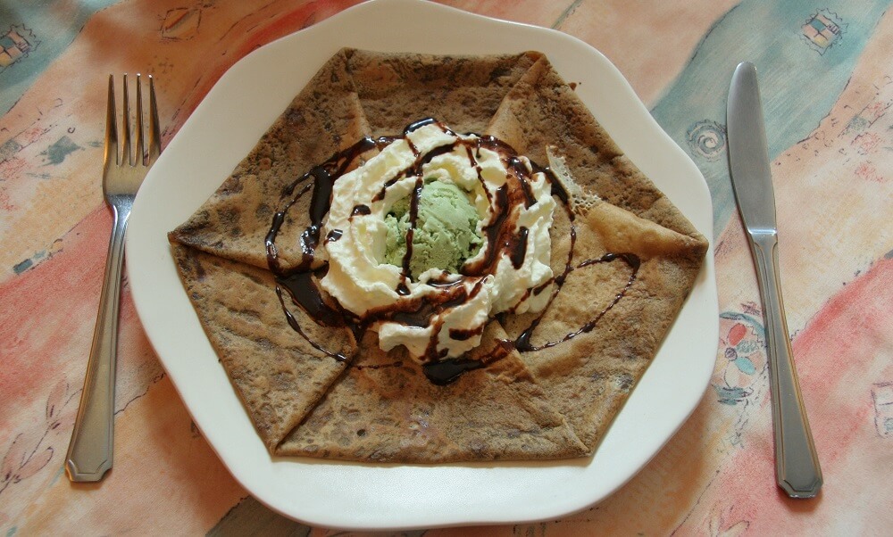 A folded crepe with ice cream, whipped cream and chocolate sauce, six sides