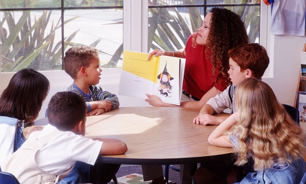 Teacher and students at round table in preschool classroom