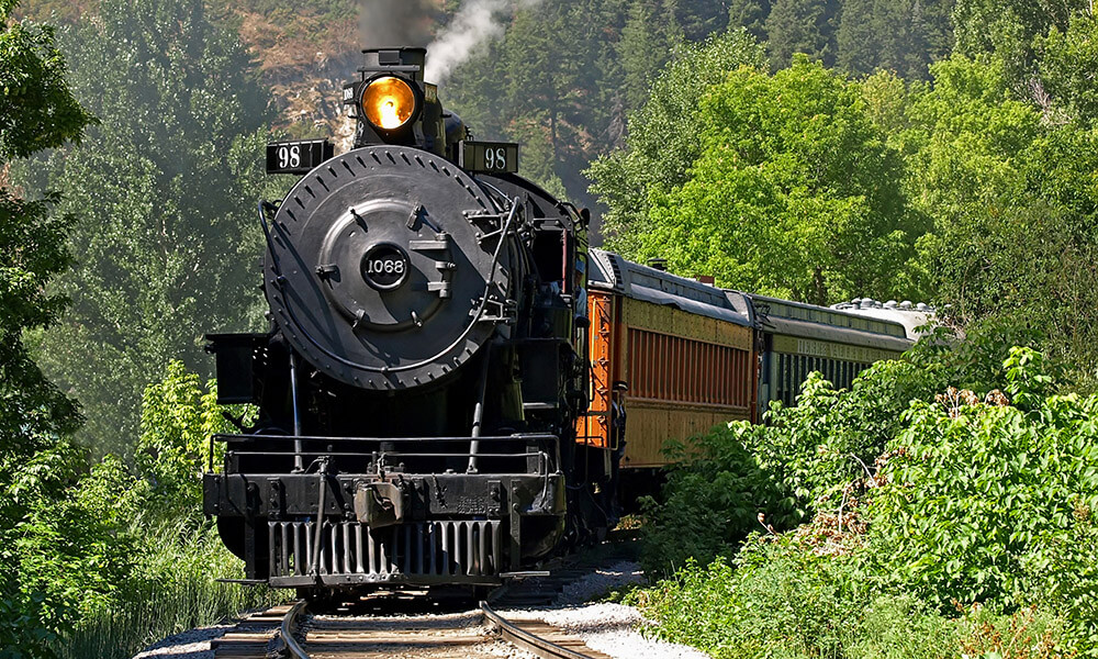Steam locomotive tourist train traveling through a canyon