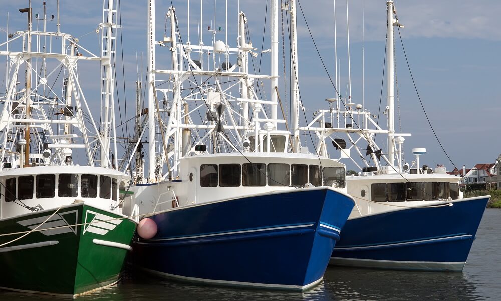 Three commercial fishing trawlers are docked for the night