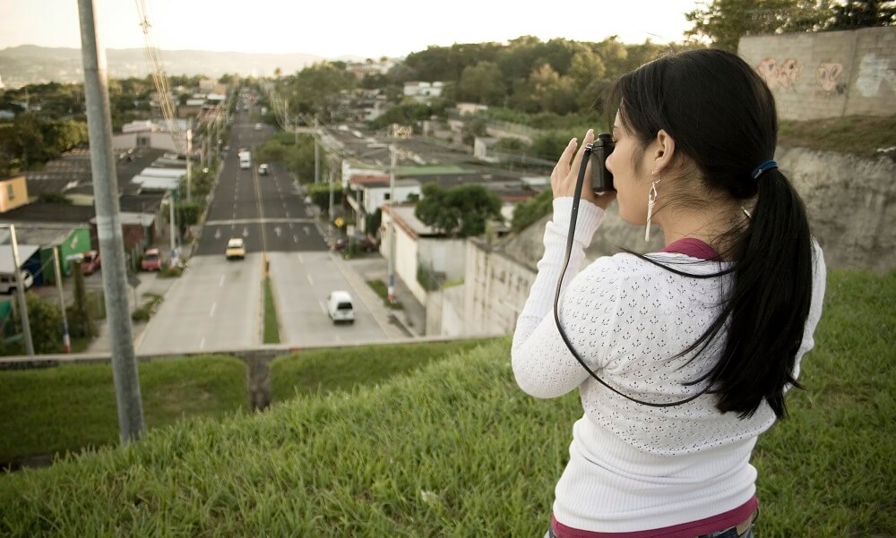 Young woman with a camera taking a picture of an urban setting