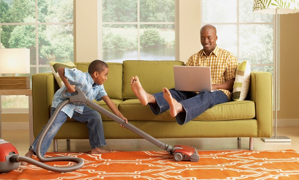 Little Boy Vacuuming Beneath his Father's Feet