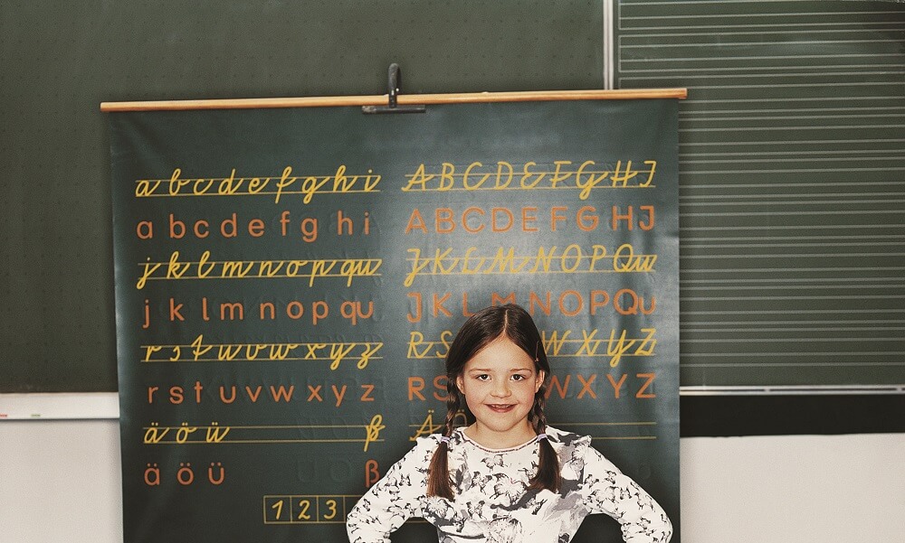 Primary school girl standing in front of a blackboard