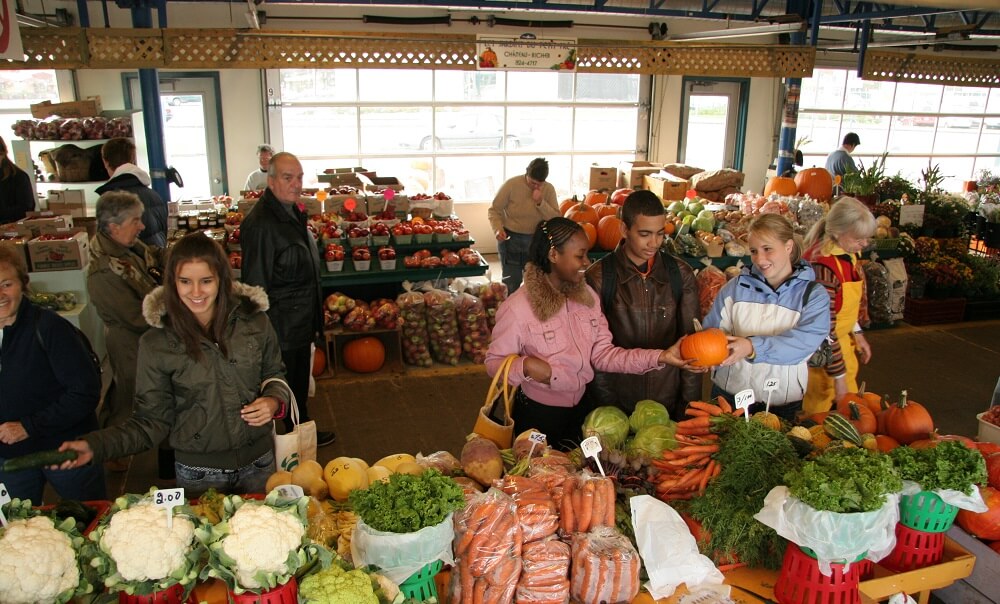Four students choose groceries at the Old Quebec public market, the Marche Public de Vieux Quebec, in Quebec City, Canada